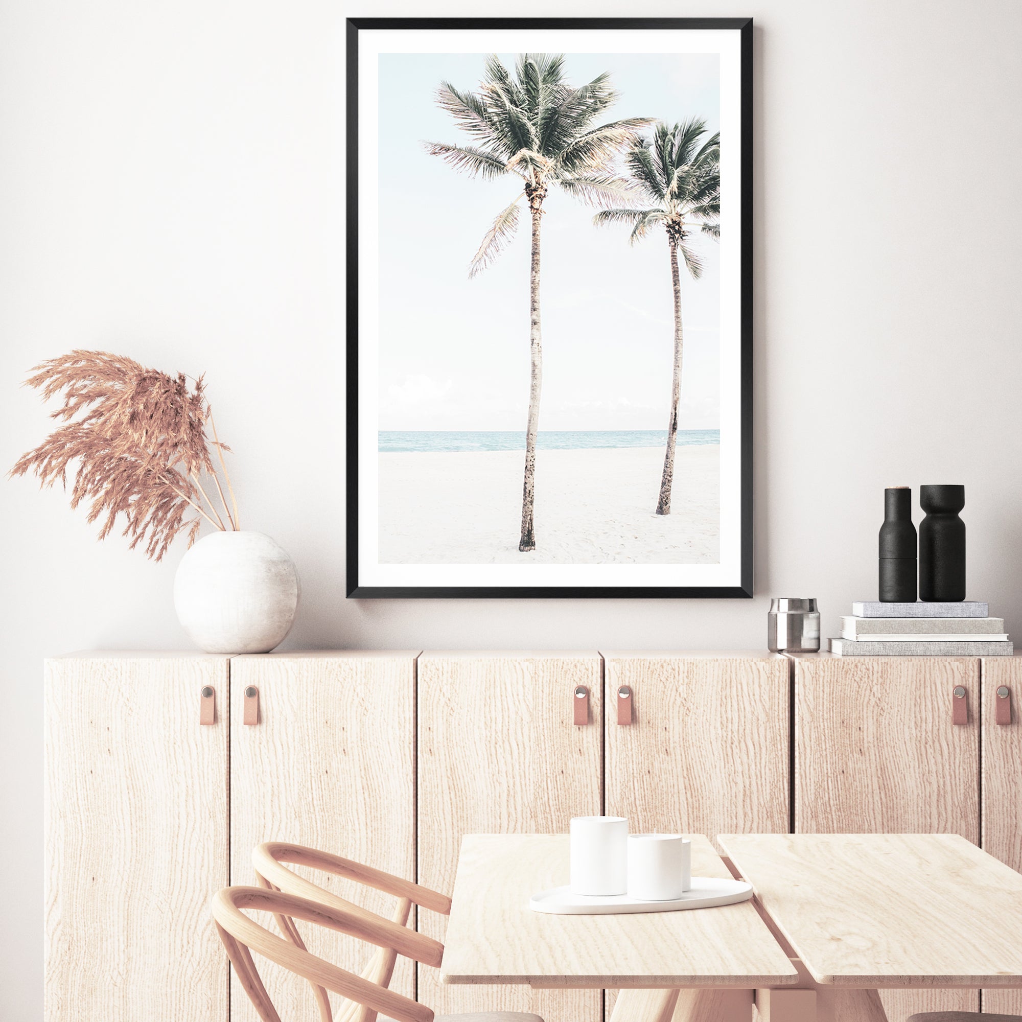 A framed or unframed stretched canvas of a coastal artwork of blue skies, two palm trees and the beach