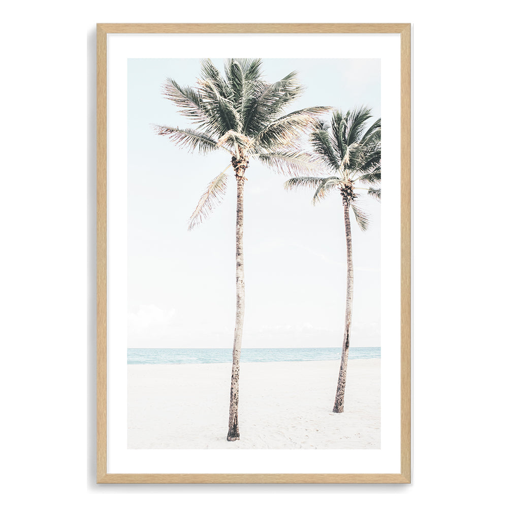 A coastal artwork of blue skies, two palm trees and the beach, available in print and canvas. 