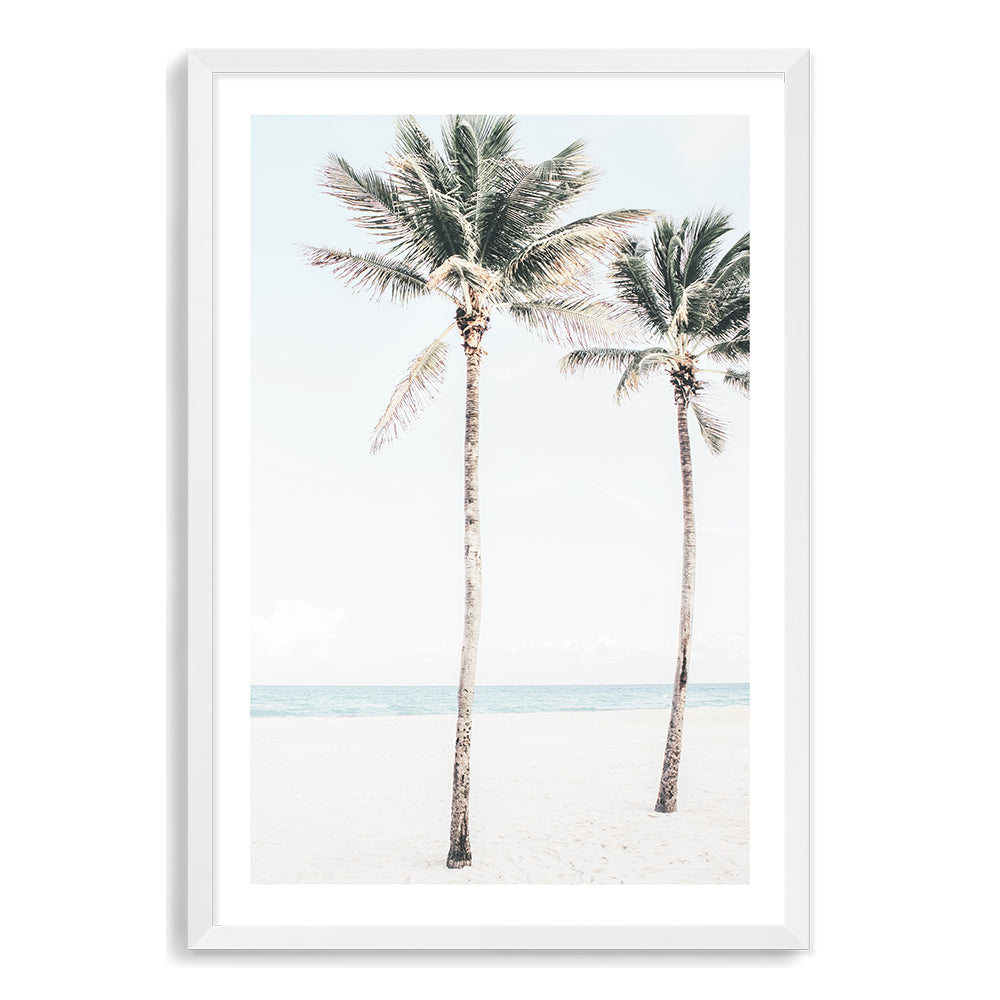 A coastal  wall art of blue skies,the beach and two palm trees, available in print and canvas. 
