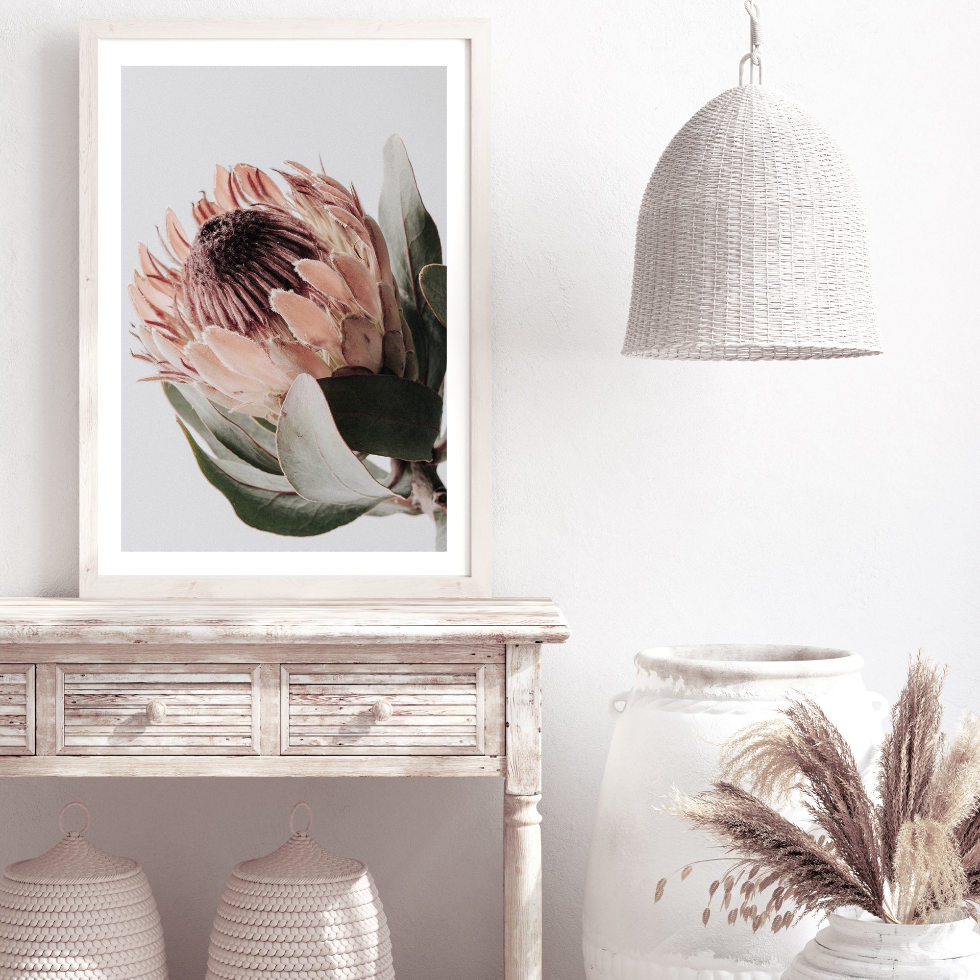A floral artwork of one beautiful peach protea flower with green leaves in muted tones in an unframed print. 