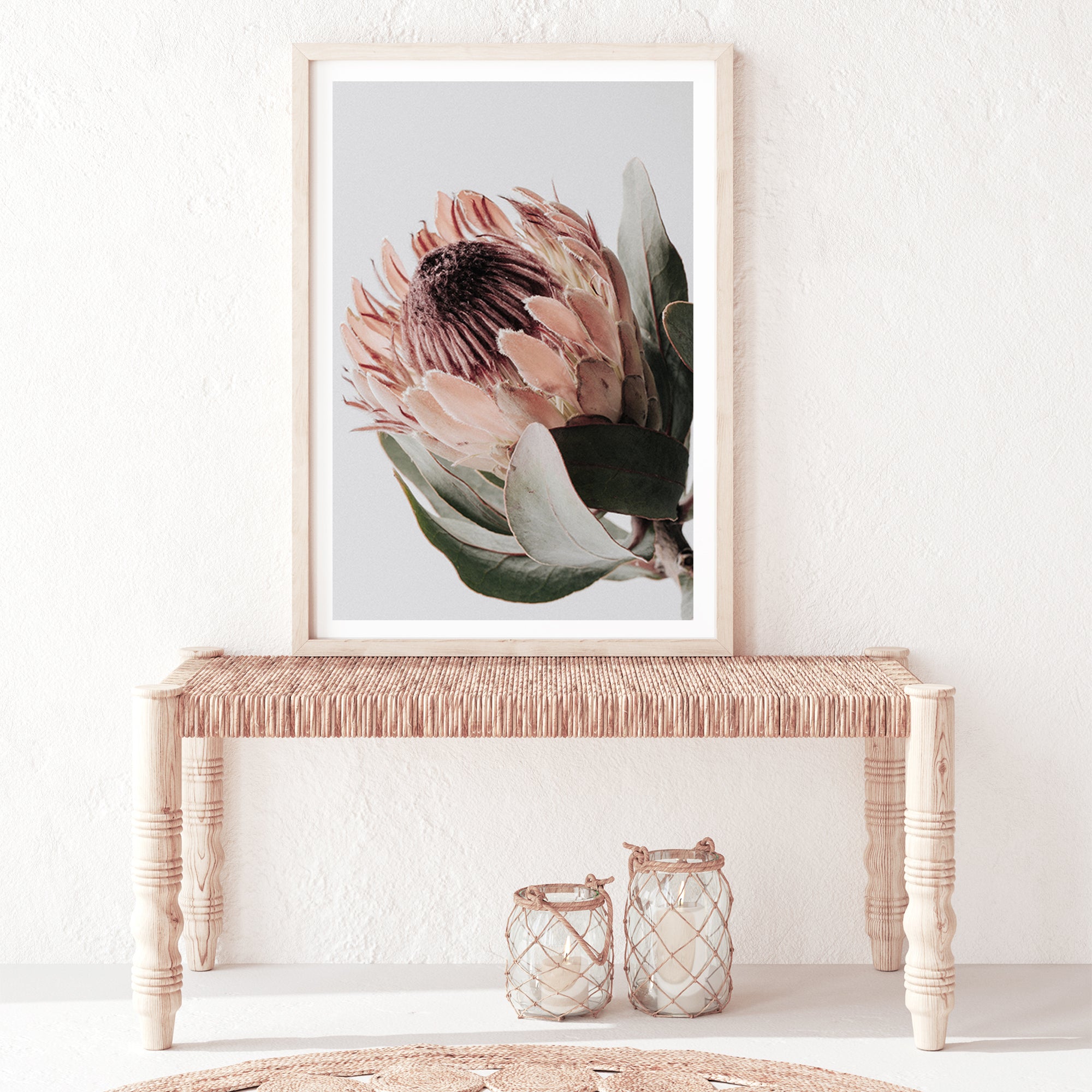 An artwork featuring a beautiful peach protea flower with green leaves in muted tones, available framed or unframed.