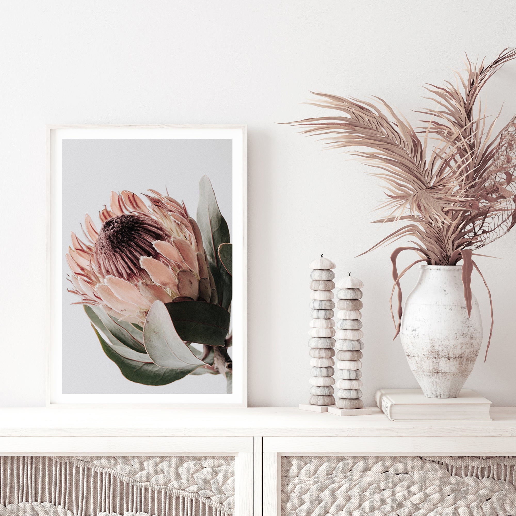 A wall art print featuring one beautiful peach protea flower with green leaves in muted tones, available unframed or framed.
