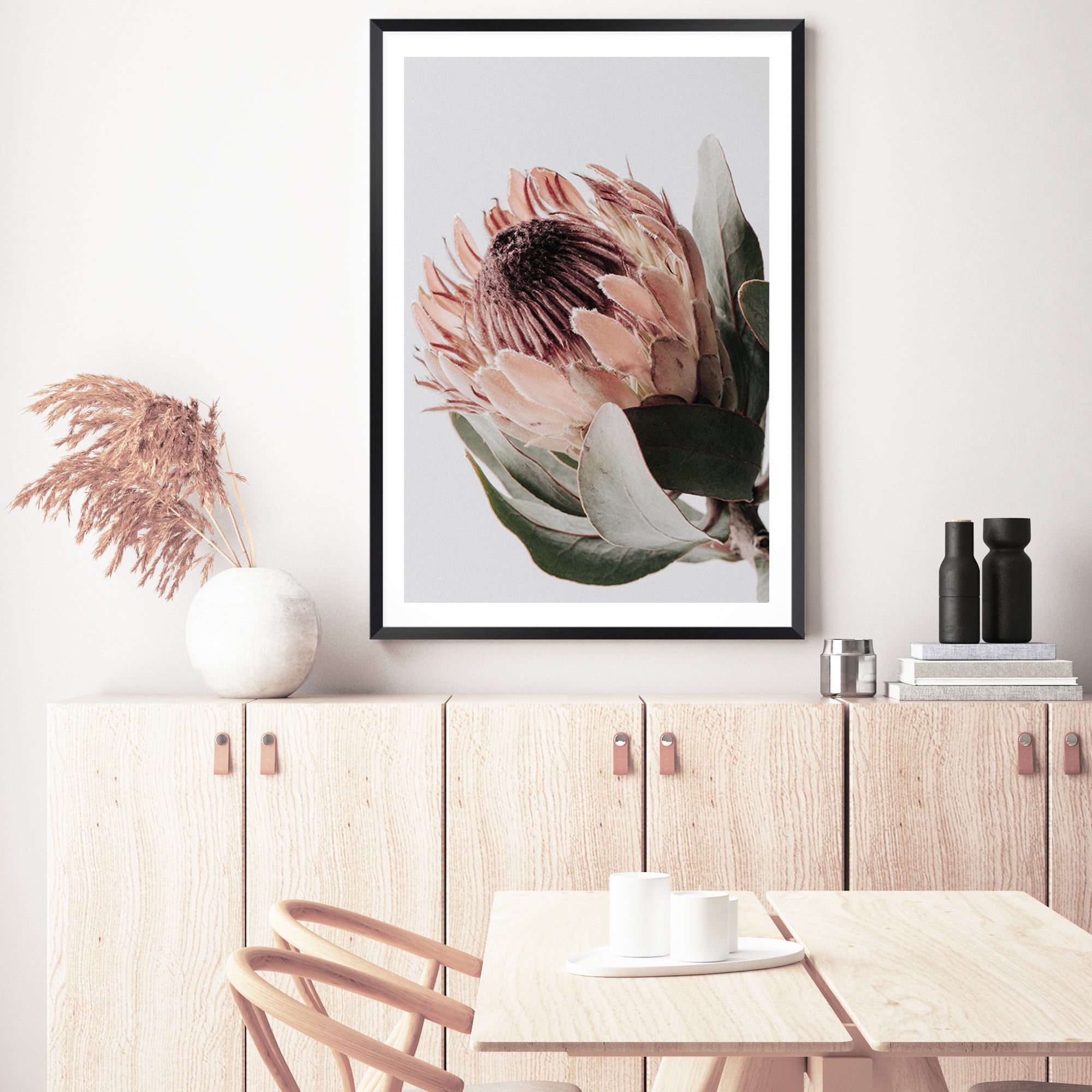 An artwork print of one beautiful peach protea flower with green leaves in muted tones available unframed or framed. 