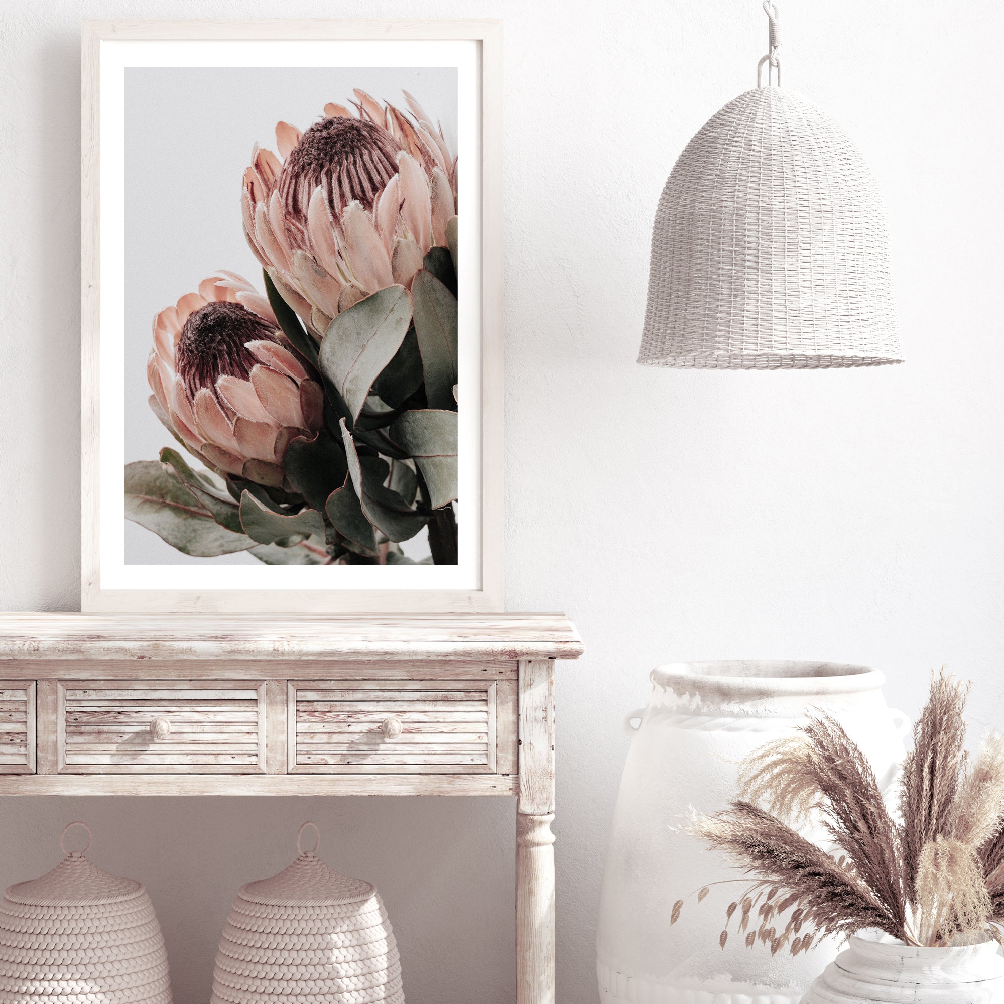 A floral artwork of two beautiful peach protea flowers with green leaves in muted tones in an unframed print. 