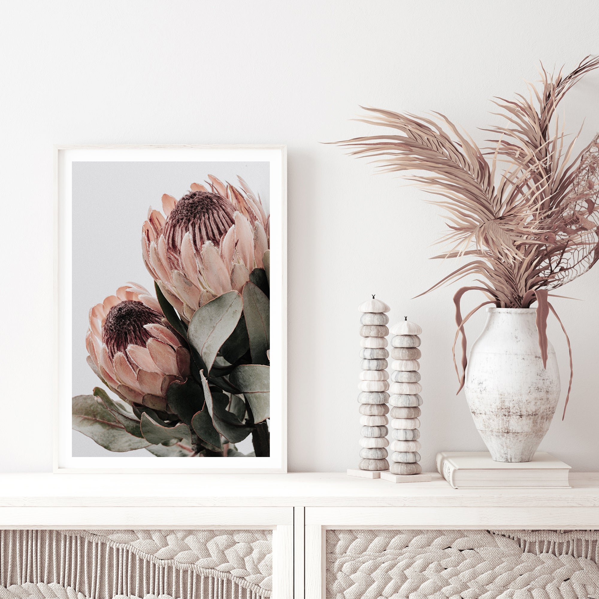 Two peach protea flowers with green leaves in muted tones are featured in this beautiful floral artwork. 