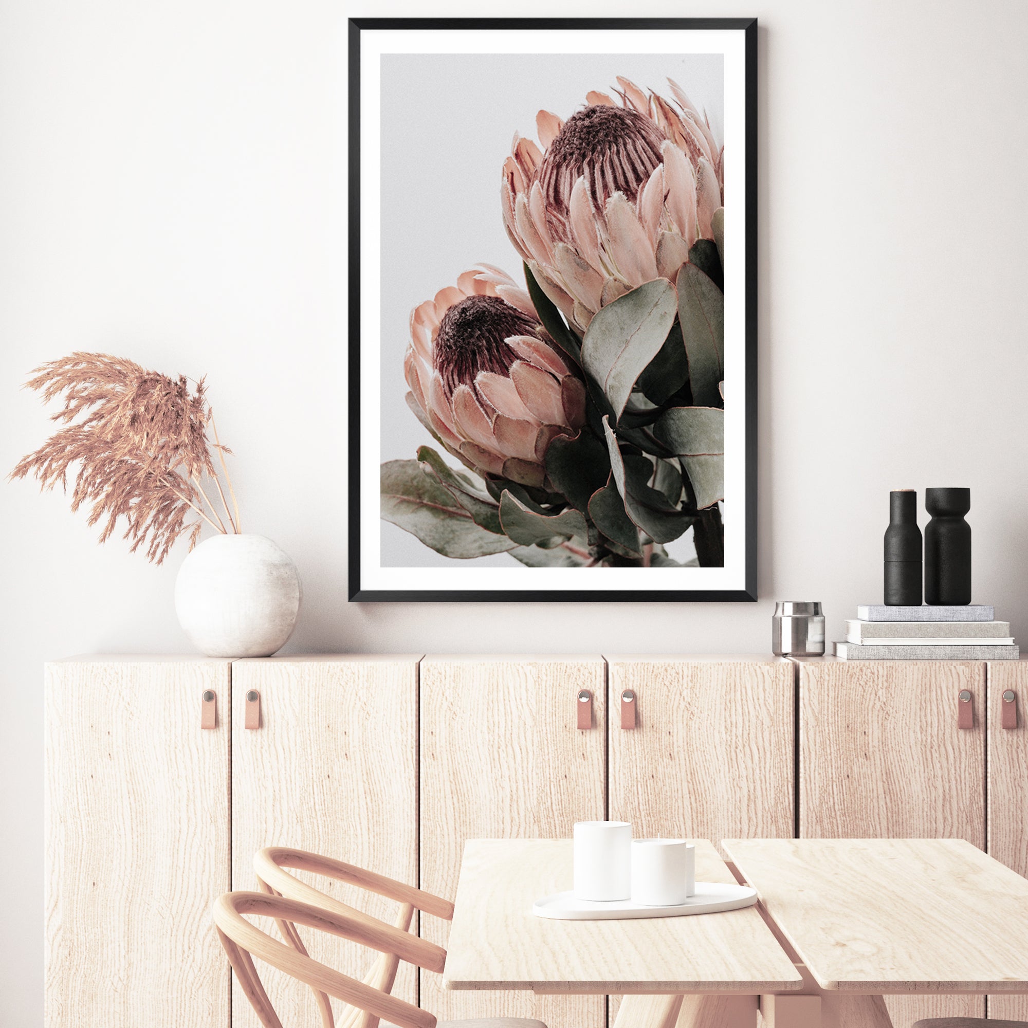 A wall art print of two beautiful peach protea flowers with green leaves in muted tones available unframed or framed. 