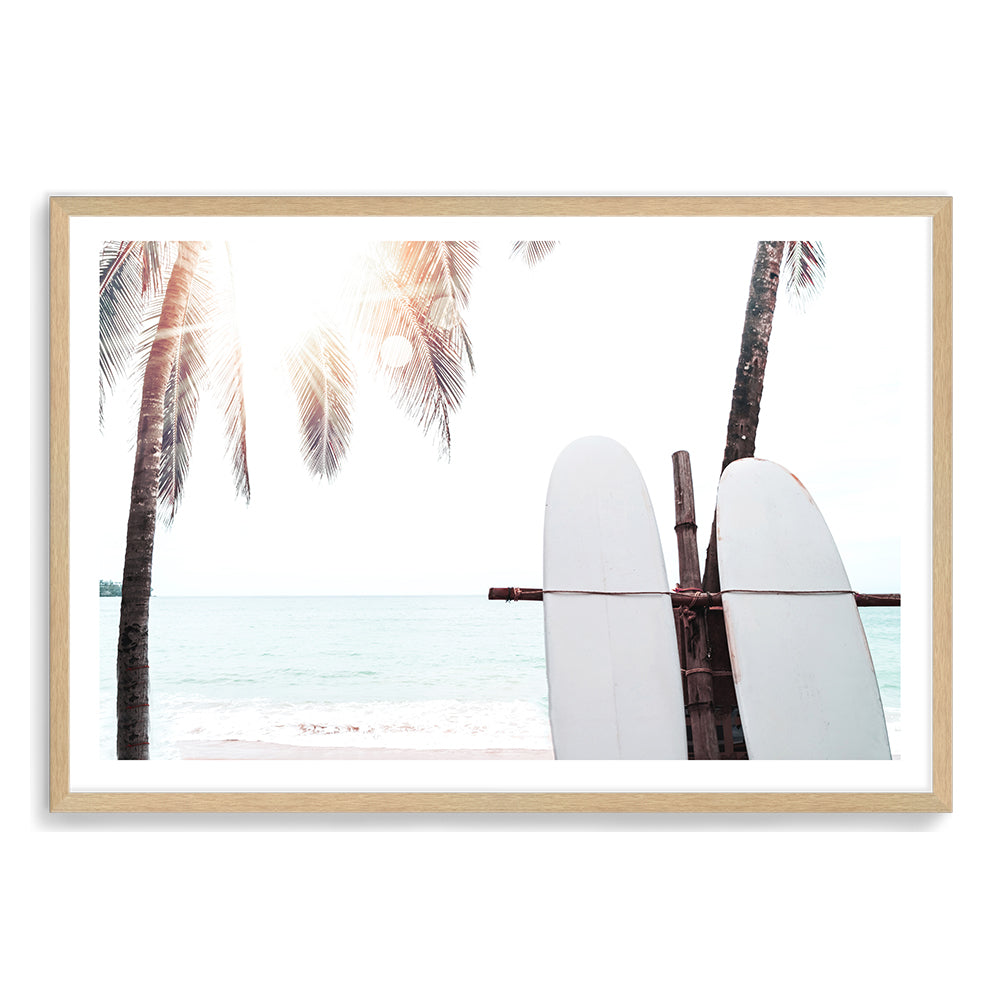 An artwork of a tropical sunset with two white surf boards under the palm trees available in canvas and art print.