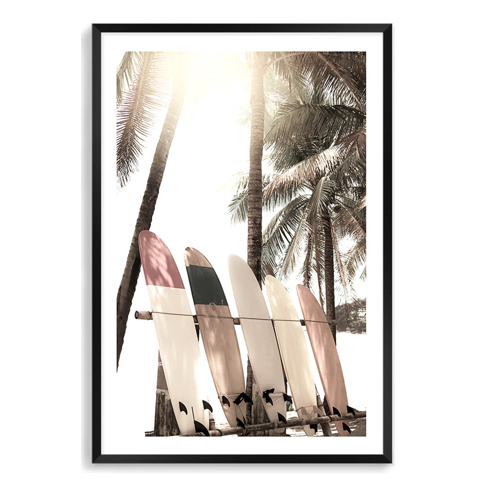 Our Surfers Sunset (B) art prints features four white surf boards on a beach under the palm trees with a view of a tropical sunset.